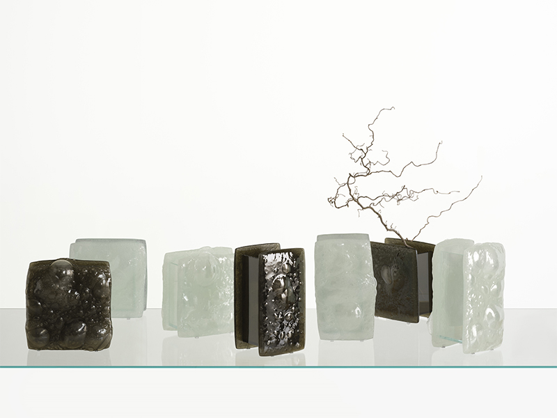 ‘Opalia’ collection of vases by Patricia Urquiola is defined by dual-sided forms, created by fusing glass scraps with special additives into irregular, bubble-rich masses and undulating surfaces, bonded to float glass sheets for functionality. (Image Credits: Courtesy of Glas Italia) 