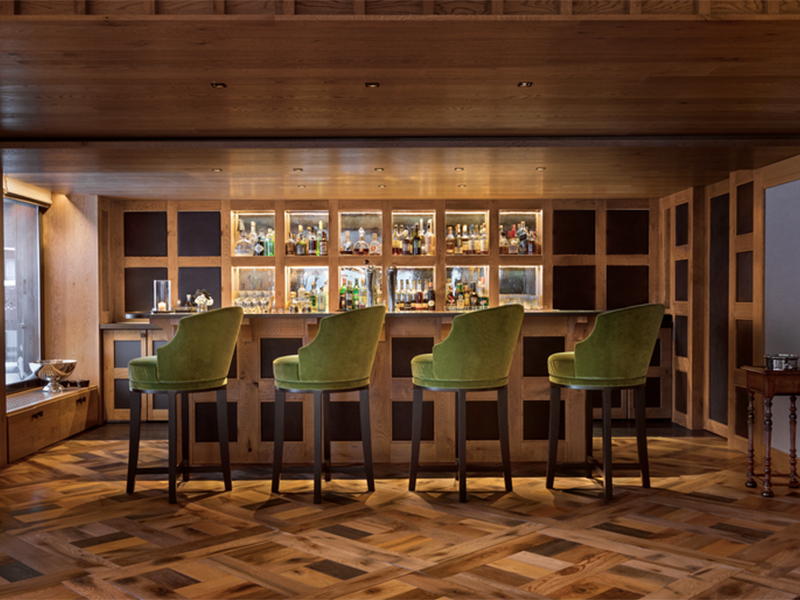 The in-house bar at Aman Le Mélézin is a friendly space with plush stools, parquet floors, and mesmerising mountain views. (Image Credit: Aman Le Mélézin)