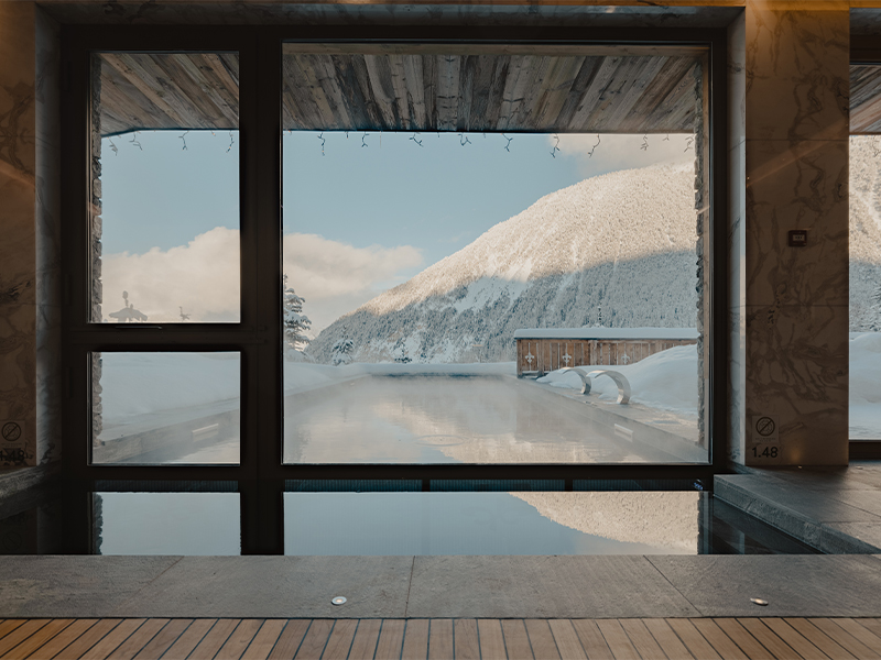 Soaking in the outdoor sauna pool as snow falls is an experience in itself, while indoors at the spa unit, expansive bay windows look onto a pine-studded stretch of mountainside. (Image Credit: Ultima Hotel Courchevel )