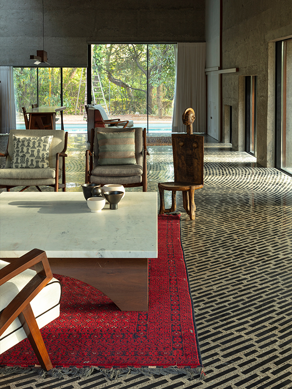 The red rug set against the concrete palette and broken ceramic chips flooring becomes the heart of the House Of Concrete Experiments, designed by Samira Rathod Design Atelier (SRDA). (Image Credit: Niveditaa Gupta) 