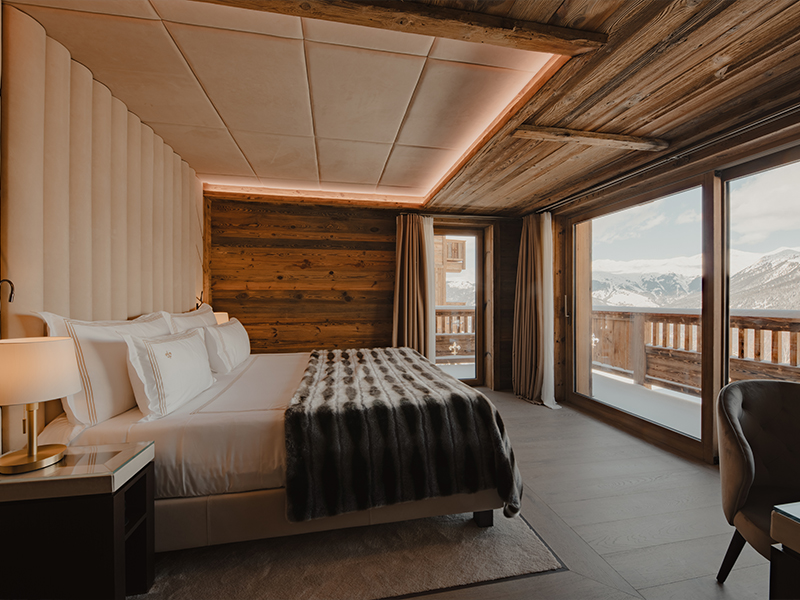 With its minimalist form, rich wood cladding, and open-concept plan, this modern chalet seamlessly brings the mountain spectacle into its intimate spaces. ( Image Credit: Ultima Hotel Courchevel ) 