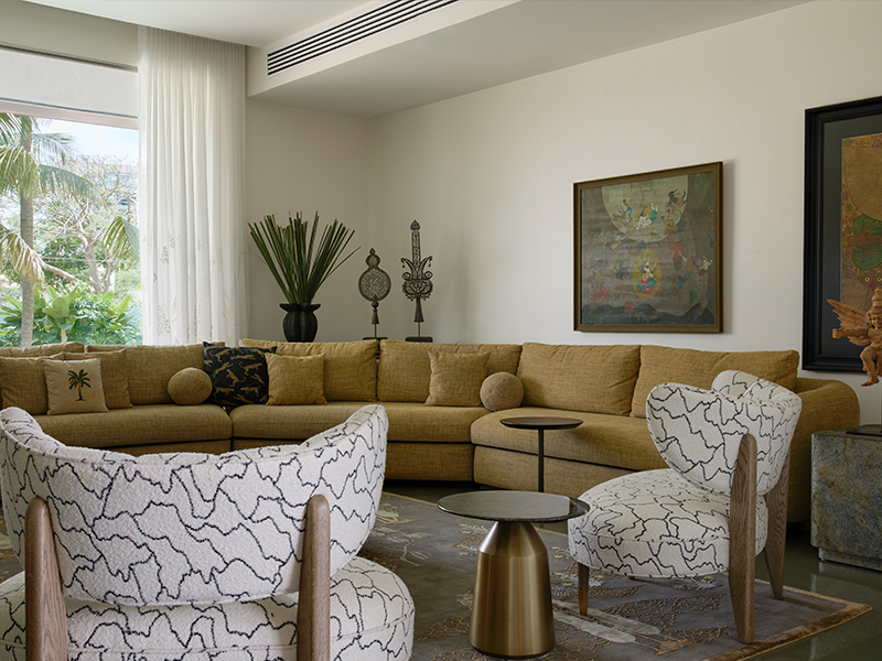 Earthy tones, feather-light chandeliers, and a curated selection of artefacts set the perfect tone for an elegant soirée. The sofa is from DeMuro Das, the furniture from K2, rugs from Jaipur Rugs, lights by Klove, vase by Rooshad Shroff, and artworks from KYNKYNY and Pinakin Studios. (Image Credits: Talib Chitalwala)