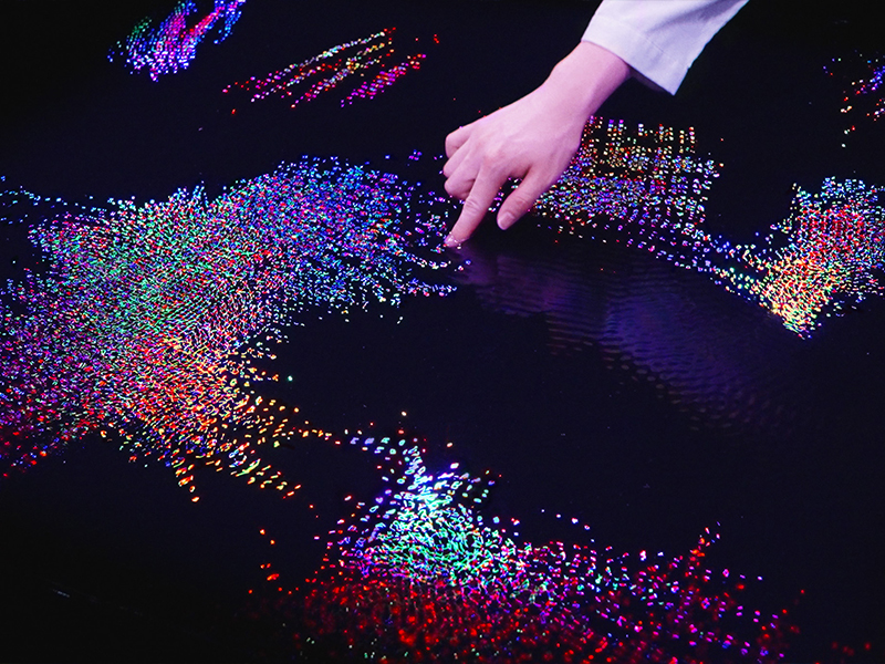 teamLab, Living Crystallised Light (2025), from the series Living Crystallised Light (2022), invites visitors to dip a finger into a glimmering pool, where ripples bloom into a dynamic mosaic of light. (Image Credits: Courtesy of teamLab and Pace Gallery) 