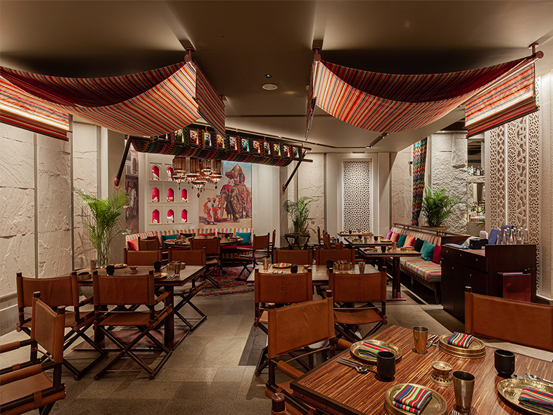 The design draws from the rich history and cultural influences of the Spice Route, with stripped durries suspended like elegant awnings, evoking the mobile tents once used by travelling caravans. (Image Credit: Fab Studio)