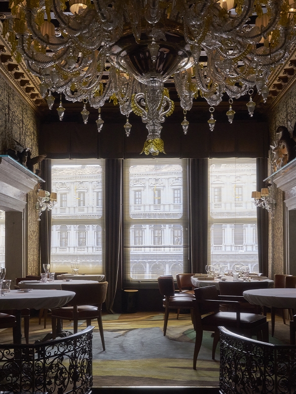 A grand Rezzonico-style Murano glass chandelier from the 1930s has been meticulously restored and now hangs beside a contemporary twin, identical in scale and style but adorned with surreal, gold-painted dripping glass details. (Image Credit: Quadri) 