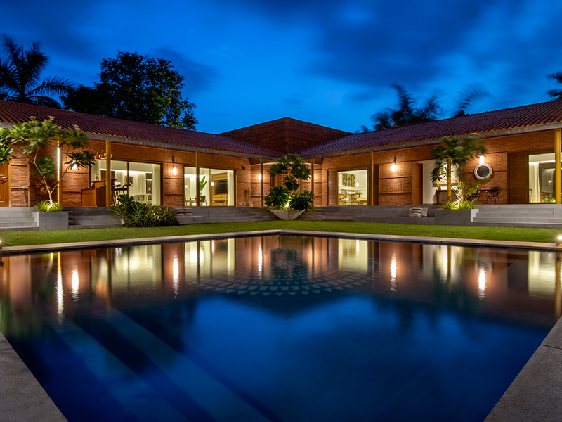 The central courtyard space encloses a pool that spills onto the lush landscape ahead. (Image Credit: Tejas Shah)
