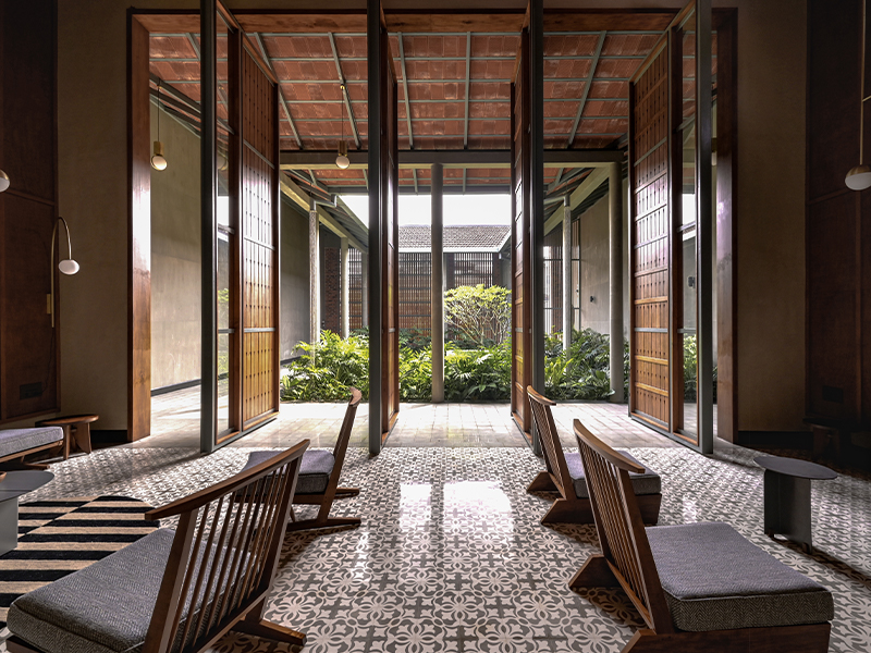 The tall wooden doors open to the courtyard while the beautifully lustrous floors from Bharat Floorings & Tiles enhance the seamless flow. (Image Credits: Roy Antony Architects) 