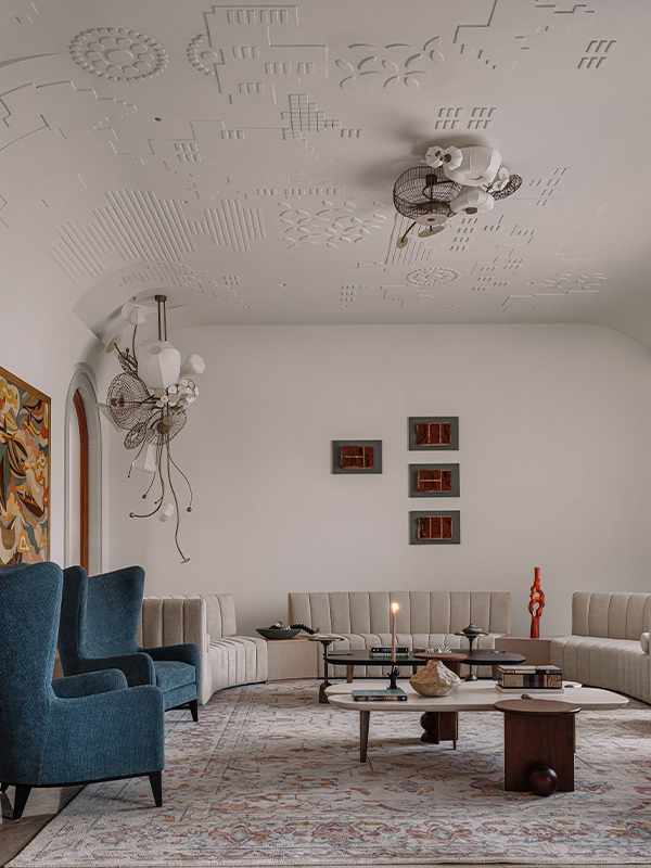 A pair of bespoke Olie lights crafted from metal, fabric and ceramic appears to pulsate from within the formal living room. The marquetry art is by Sameer Tawde. (Image Credits: Ishita Sitwala) 