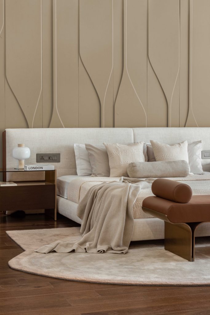 In the master bedroom, a side table and day bed from Maanavi Homes are positioned alongside leather panelling by Leather Art and teak flooring by Mikasa Floors, creating a rich interplay of texture and tone. (Image Credits: Purnesh Dev Nikhanj)