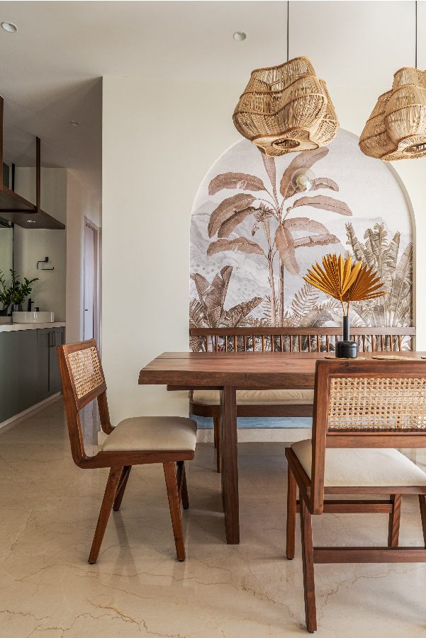 The richly grained dining table, side bench and chairs are made on-site. The bamboo light fixtures are from Luuma lights. The botanical wallpaper was picked from Metamorph. 
(Image Credits: Aditya Warlikar)
