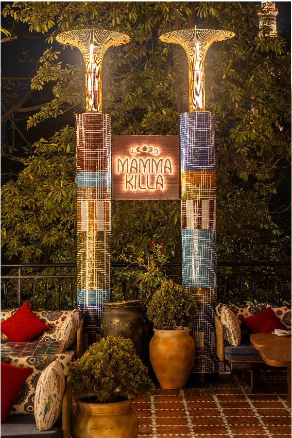 Twin mosaic columns stand like sentinels, bearing the name ‘Mamma Killa’ surrounded with lush green planters. (Image Credits: Courtesy of Mamma Killa)
