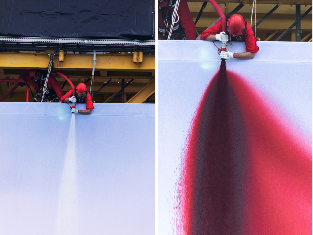 Left: A Greenpeace climber spraying a high-pressure hose on the 12 x 8-metre canvas. Right: The blood-red liquid sprayed from the hose is a concoction of seawater, beetroot powder and non-toxic food-based dye. (Image Credits: Greenpeace)

