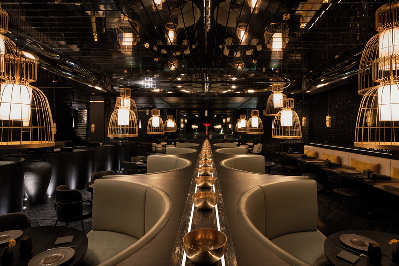 Ai Kissu’s striking fire cauldron, paired with brass, wood, and a mirrored ceiling, blends seamlessly with the dimmed lights and furnishings—bringing an Asian sensibility with a glint of modernist style(Image Credit: Tom Fallon) 
