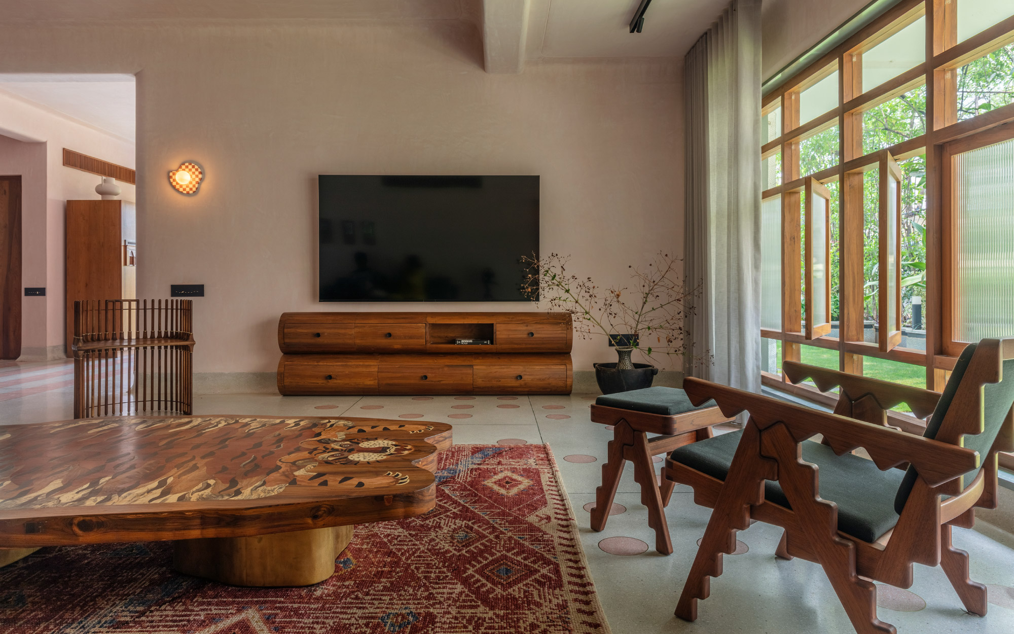 The living area features a Kilim-style rug from Obeetee, a bespoke coffee table with tiger motif from Room Therapy Collective chair and footstool from Phantom Hands, multi-leg wave-form chair from Room Therapy Collective, and veined marble wall sconce from Leviosa Design. (Image Credit: Pankaj Anand)