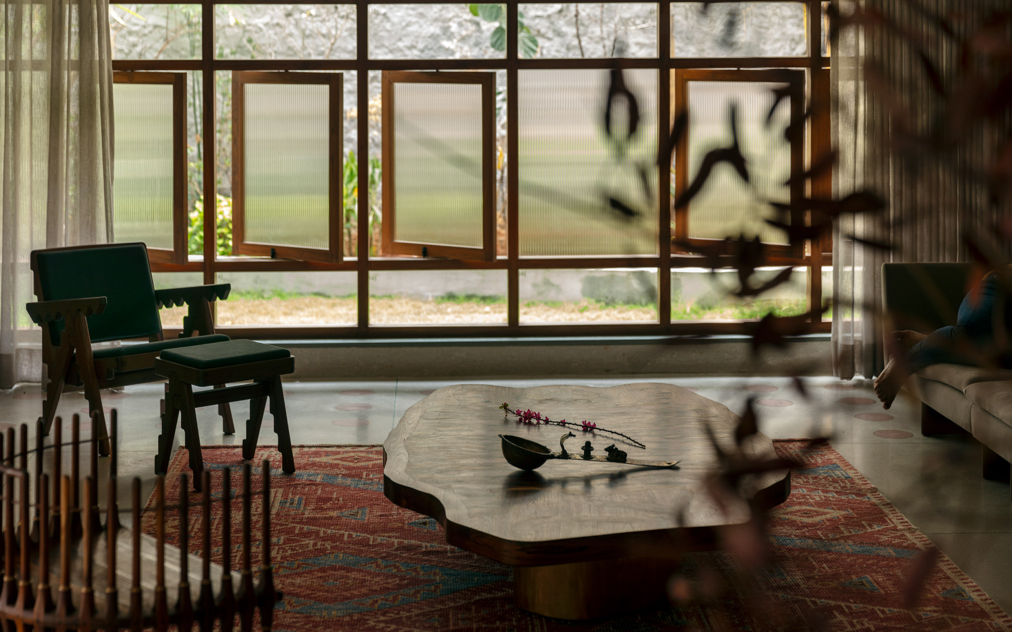 The cosy television lounge, a relaxed environment framed by floor-to-ceiling glass. The footstool is from Phantom Hands and the multi-leg wave-form chair is from Room Therapy Collective. (Image Credit: Pankaj Anand)