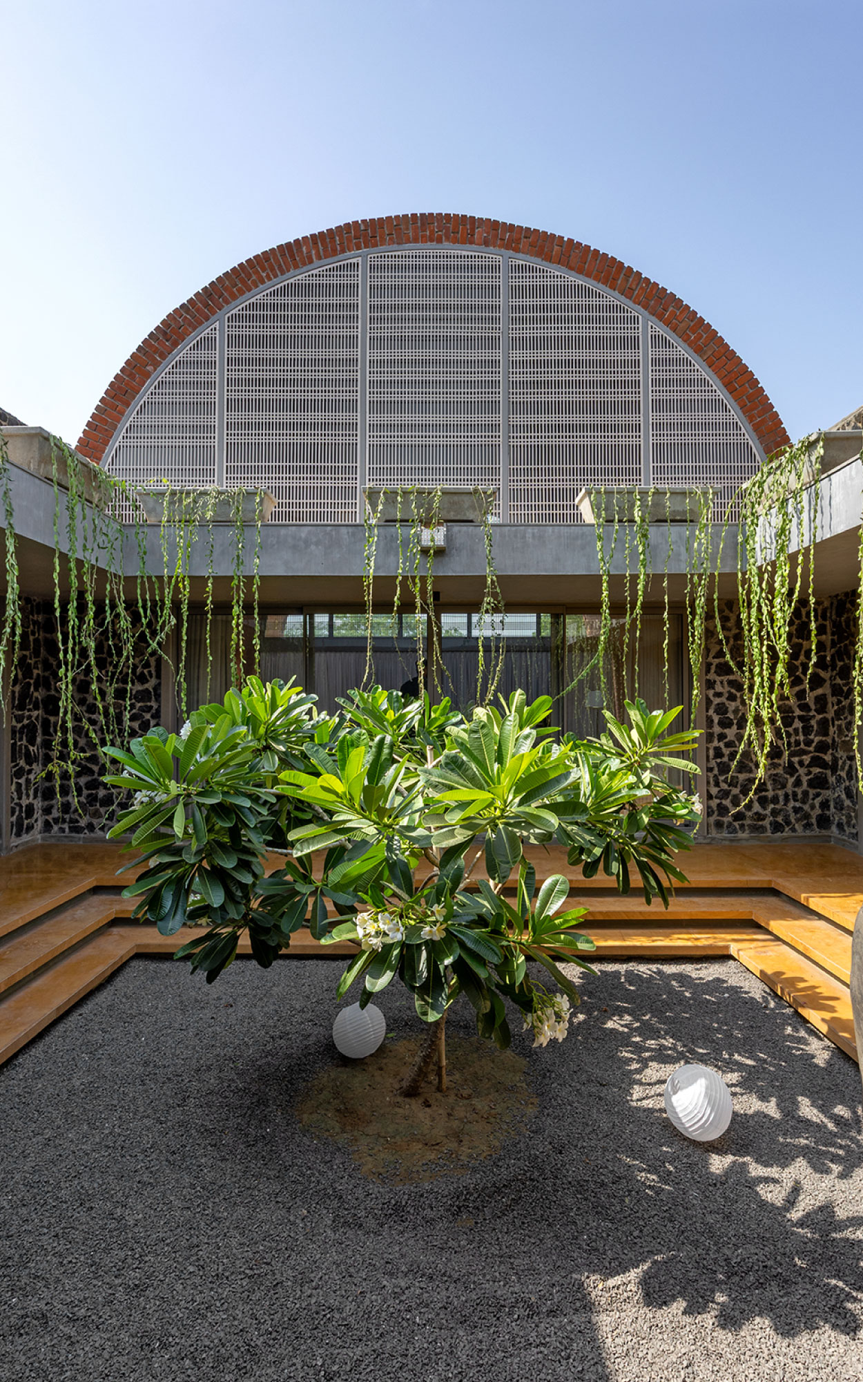 The central courtyard invites natural light, lets hot air rise and escape, and draws cooler air through shaded corridors. The decks step down into the land’s natural contours, softening its boundaries. (Image Credits: Tejas Shah)