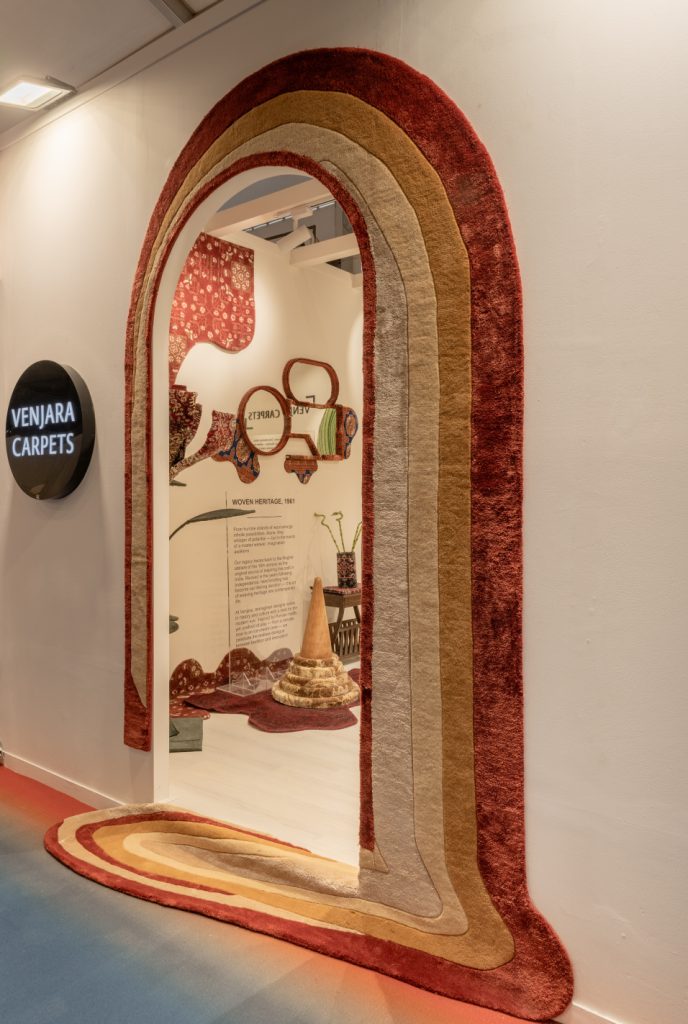 Carpets take centre stage at Venjara’s booth, adorning walls, lights, and furniture with effortless artistry. (Image Credits: Harsheen Mengar)