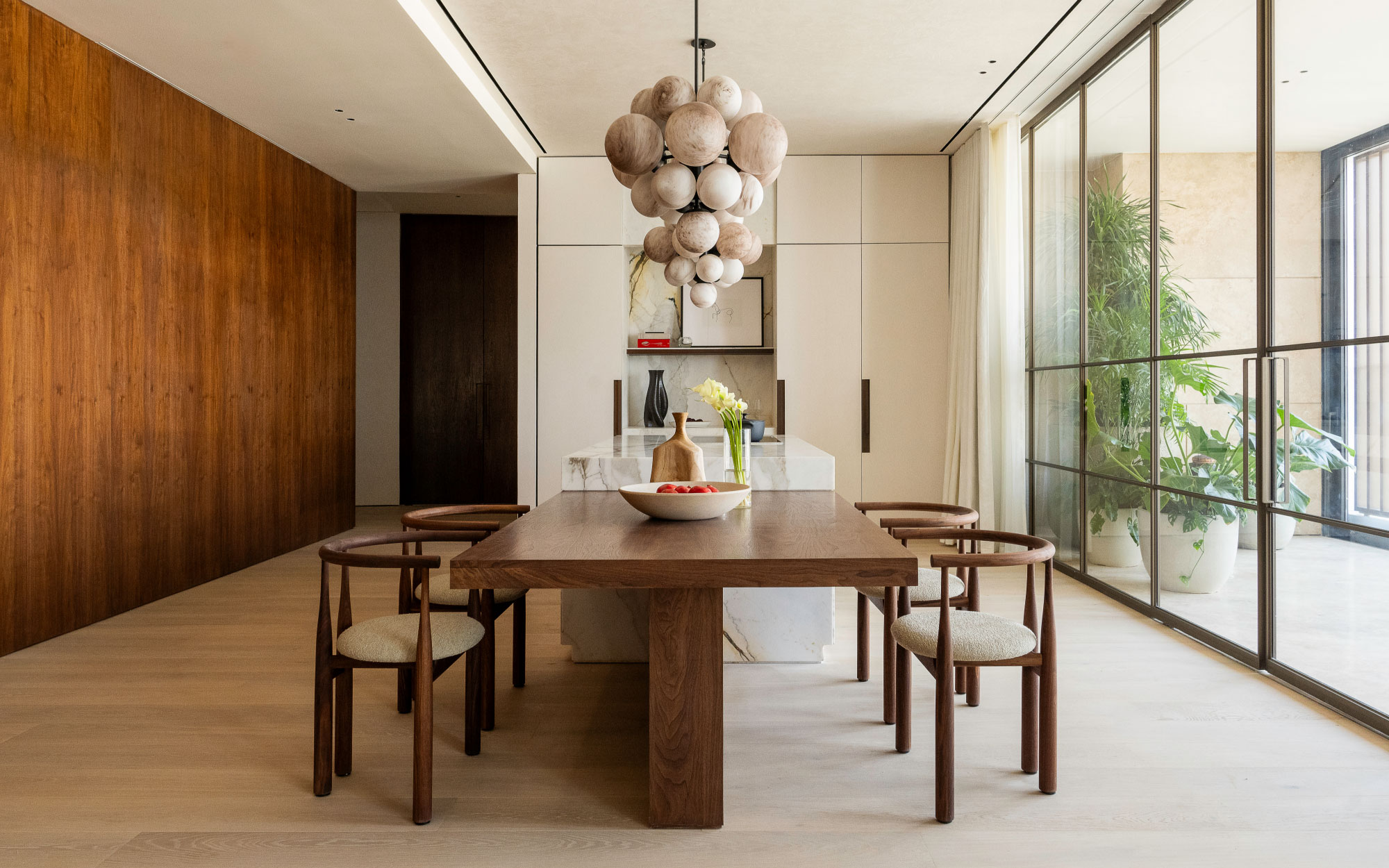 The kitchen and casual dining space features built-in storage that holds a wash basin, coffee machines and more. The dining table and countertop were crafted from scratch, while the chairs are by New Works and the pendant chandelier is by Schwung. (Image Credit: Patricia Goijens)