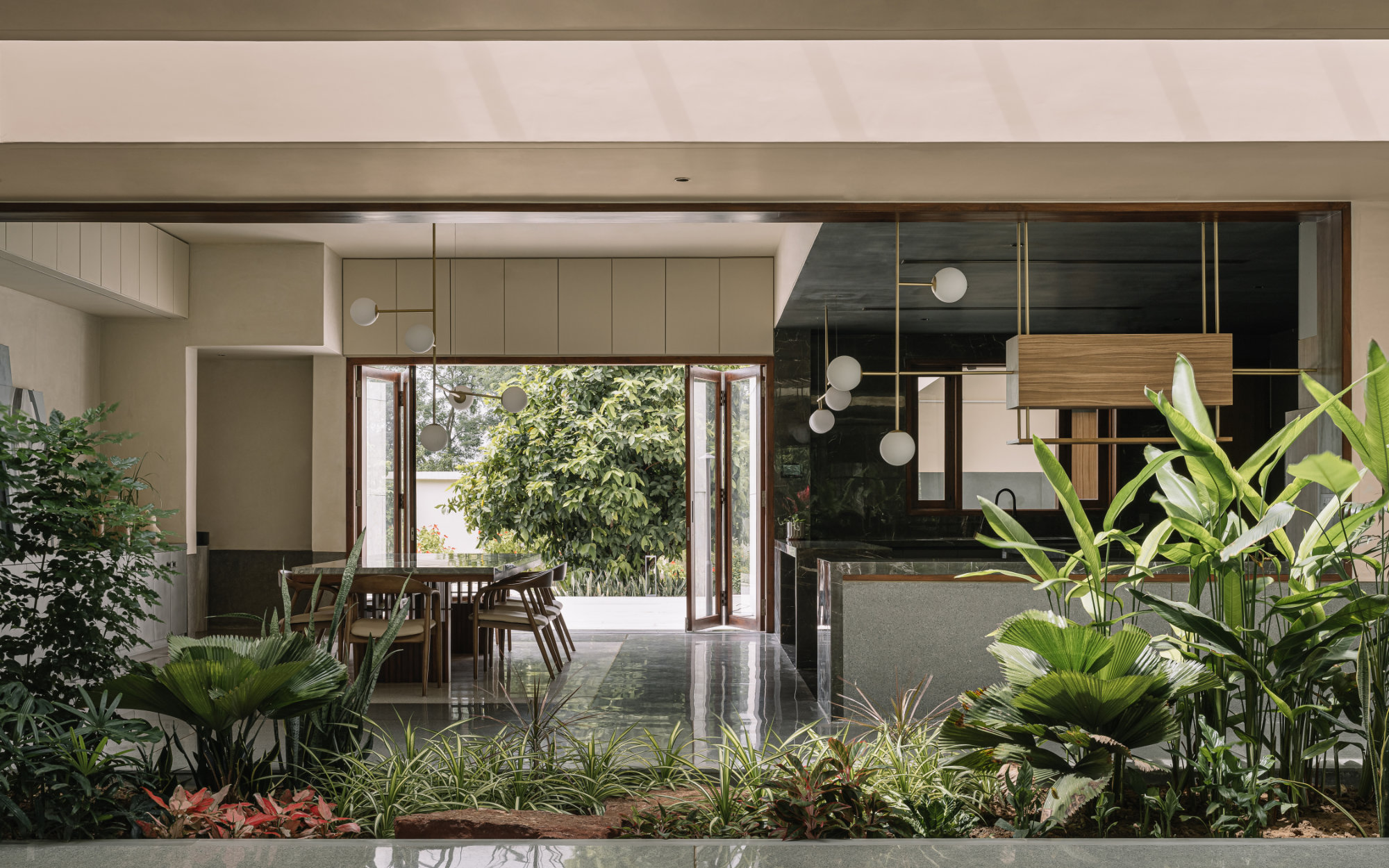 This central courtyard functions as the spatial lungs and features custom-designed brass and wooden light fixtures by Crystal Palace, Cast-in-Situ terrazzo flooring, and terrazzo landscaping elements that extend the material continuity from interior to exterior. Landscape by Jinal Patel. (Image Credits: Ishita Sitwala)