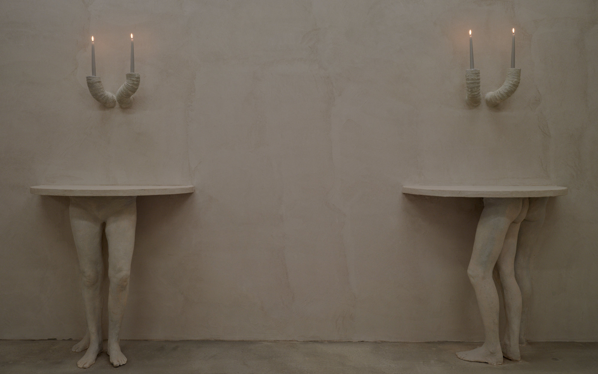 Disembodied lower limbs rise from the floor, bearing the tabletops like twisted, living pedestals. (Image Credits: Jasper Fry) 