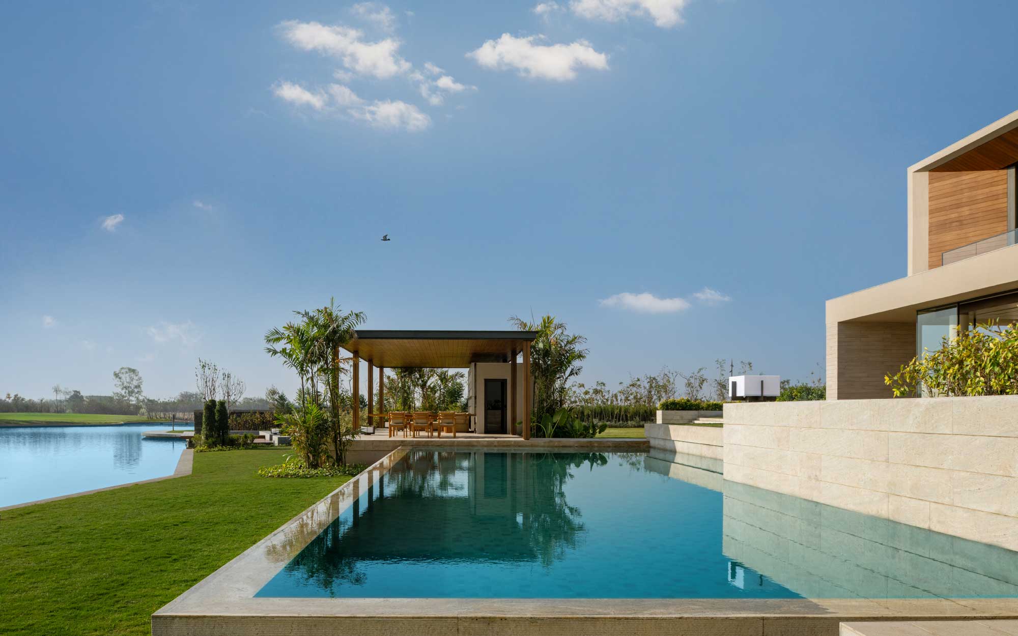 The lake and reflective pools act as the estate’s natural moderators, their presence cooling the air and shaping a softer microclimate. (Image Credits: Suryam Developers) 